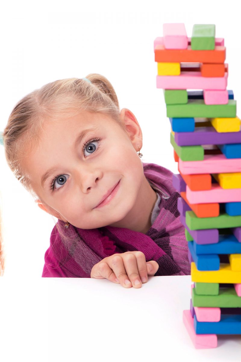 children-s-hobbies-creativity-little-girl-in-blue-dress-playing-with-the-wood-game-jenga-on-white-background