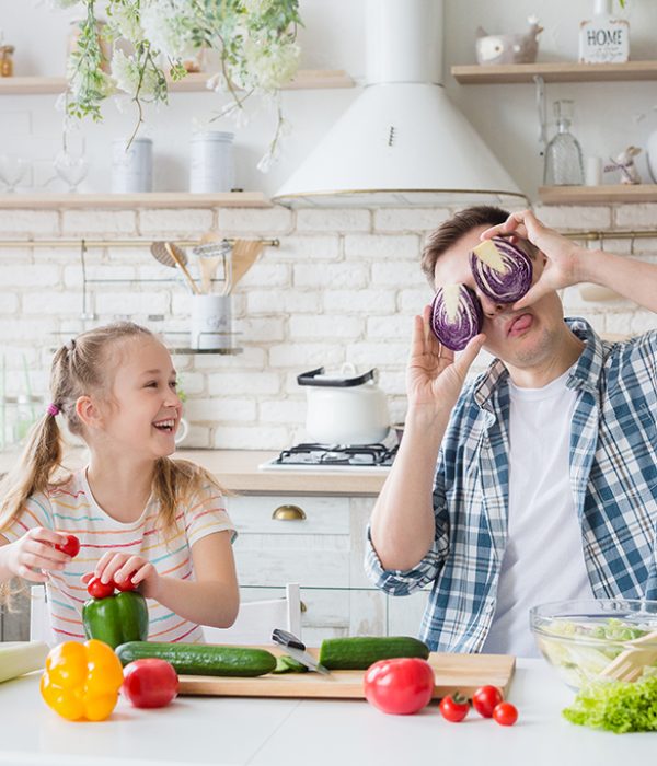 Cute little girl and her dad having fun while cooking in kitchen at home