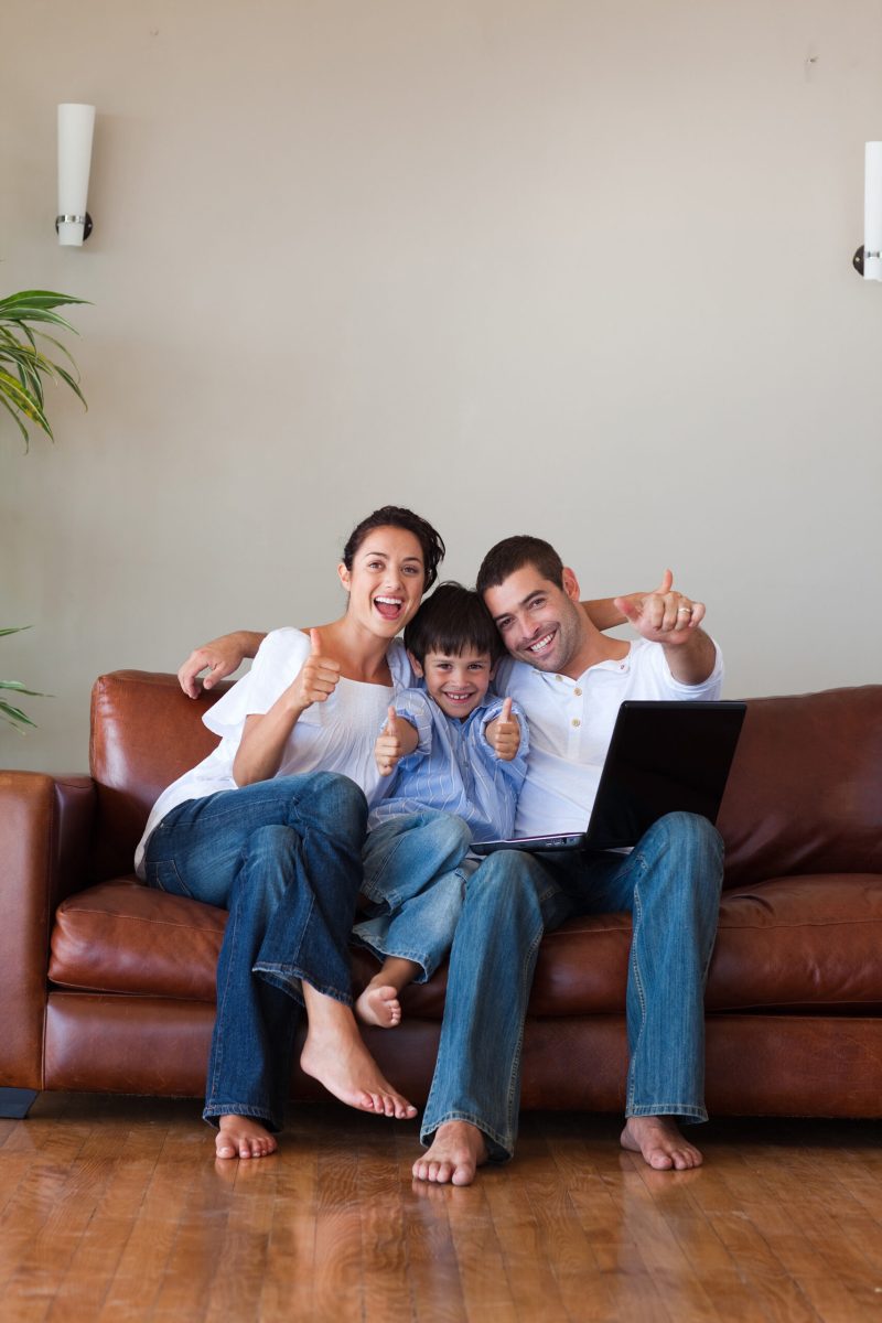 Parents and kid having fun with a laptop at home and copy-space