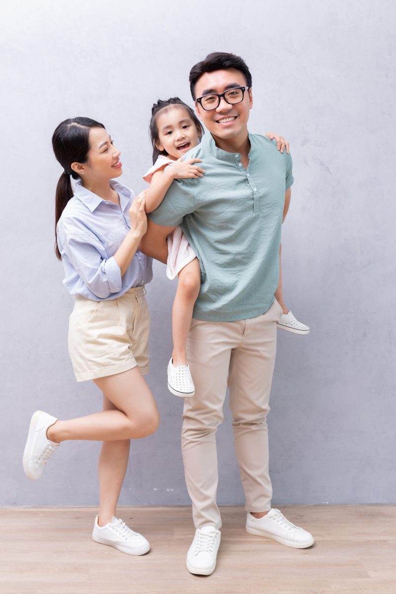 Young Asian family standing on background